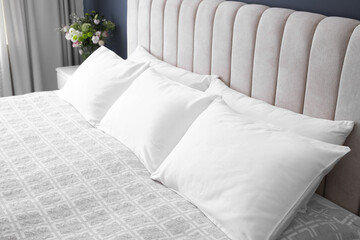 Comfortable bed with soft pillows indoors, closeup