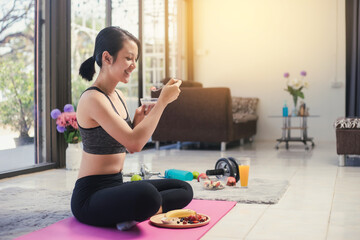 Healthy Asian woman happy smiling in sportswear eating healthy breakfast. Eating diet and exercise relaxation concept.