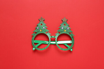 Funny glasses in shape of Christmas tree on red background, top view