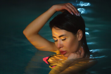 Night portrait of brunette woman swimming in pool with hot mineral water in balneotherapy spa....