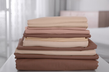 New clean folded bed linens on table indoors