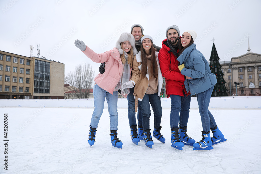 Wall mural happy friends at ice skating rink outdoors