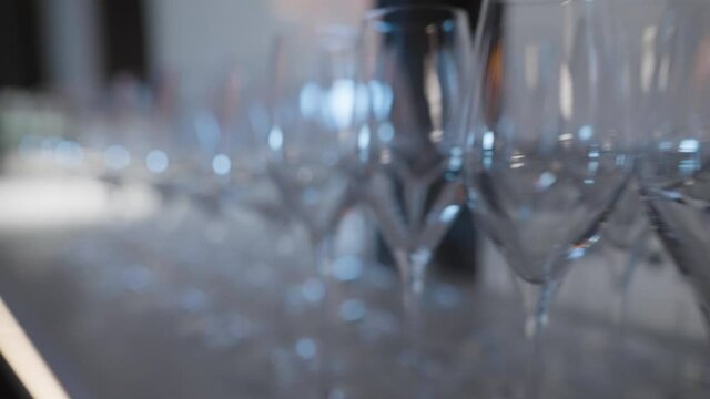 Close-up of lot of wine glasses for wine and champagne. Action. Banquet row of empty wine glasses for drinks before holiday. Rows of empty wine glasses on banquet table