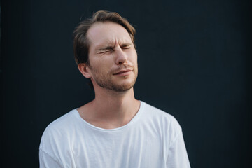 A man is saddened with closed-eyes at dark wall