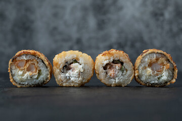 Mini sushi rolls with mixed ingredients on black background