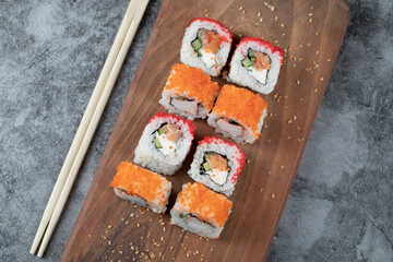 Sushi rolls with red caviar on a wooden board