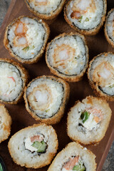Hot sushi rolls on a wooden board