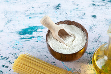 Uncooked spaghetti pasta with flour and oil bottle on white background
