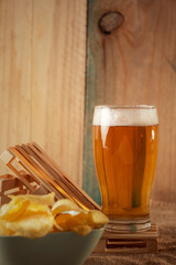 Lager beer on a industrial place ready to drink. Chips in a blue bowl for snack.