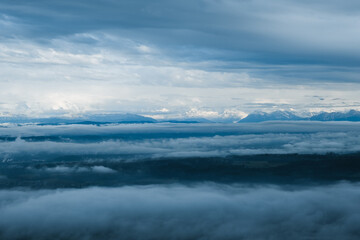 view to the swiss alps with clouds above and fog below