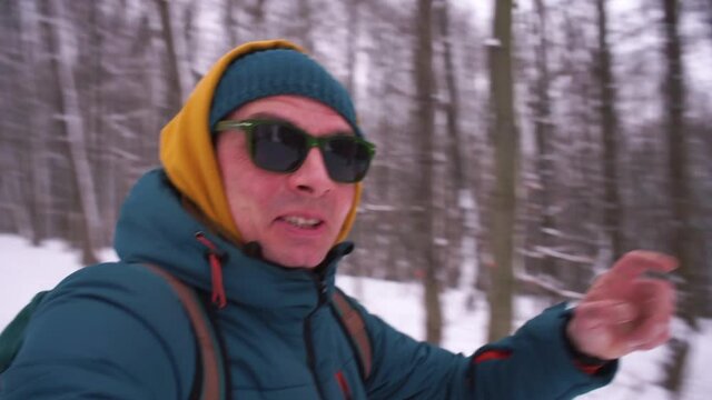 An active man runs and makes a video for blog in winter. He transmits verbal information to subscribers in motion, holds the camera with his hand. Shaking.