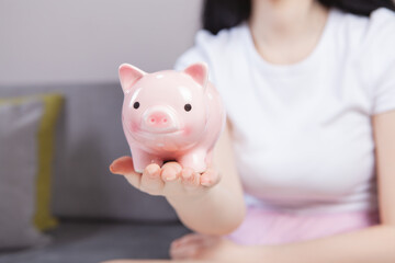 Young woman  putting a coin inside piggy bank as savings for investment