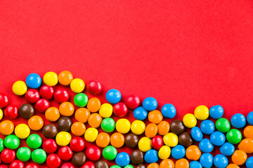 M&M's candy on the red background, colorful candy, multicolored gradient