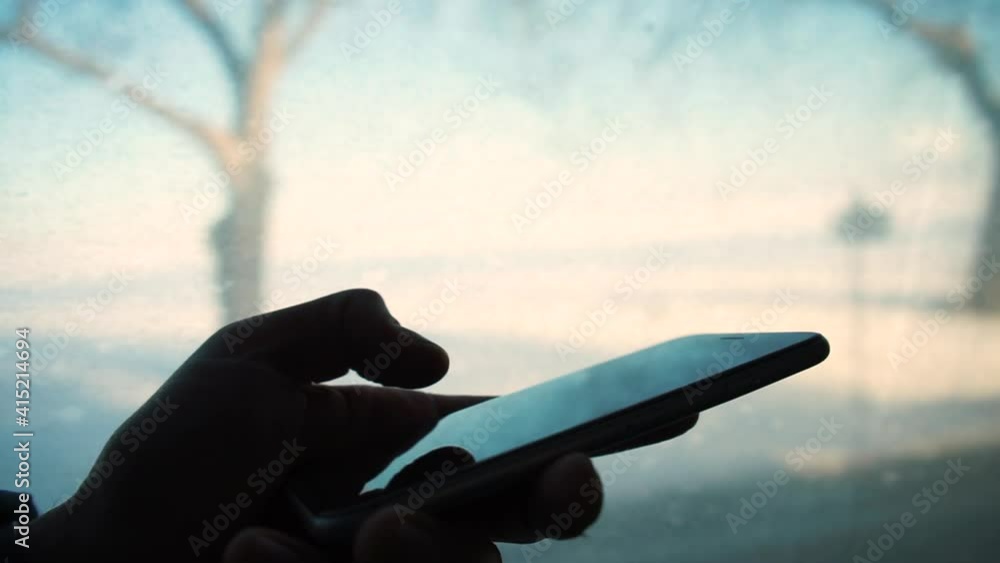 Poster silhouette hand uses the phone in public transport traffic. the finger scrolls on the screen, the ap