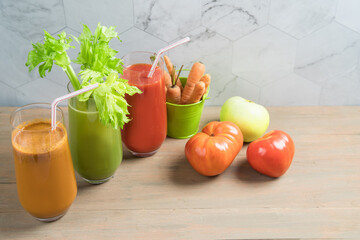 Vegetable juices of carrot, celery and tomato on a wooden background in tall glass glasses. Healthy Eating Concept