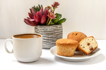 homemade mini cupcakes with raisins and a cup of coffee on a white surface