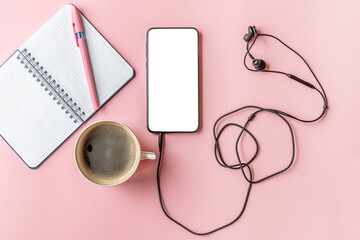 cup of coffee, smartphone, headphones, notepad and pen on a pink surface, mock up, flat lay