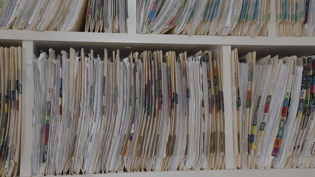 Medical cards on shelves in hospital. Health insurance folders in archive files. Records and catalogs in medicine clinic. Patient healthcare information