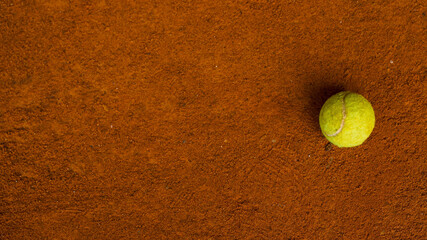 Tennis ball on the orange ground in a tennis court