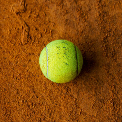 Tennis ball on the orange ground in a tennis court
