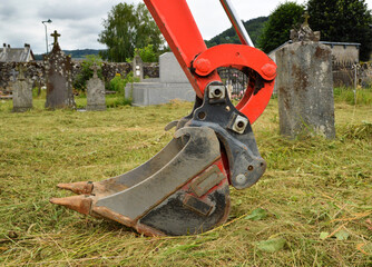 An excavator for digging a grave in a cemetery for burial or exhumation.