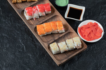 Sushi set on a wooden platter with soy sauce, ginger and wasabi