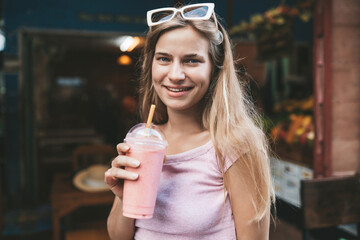 Young blonde woman drinking strawberry shake
