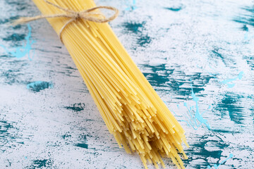 Uncooked spaghetti pasta tied with rope on colorful surface