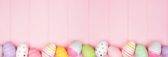Colorful Easter Egg bottom border over a soft pink wood banner background. Top down view with copy space.