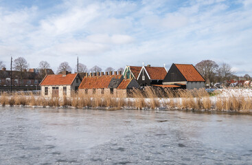 A group of small old Dutch houses on the shore of an ice-covered lake