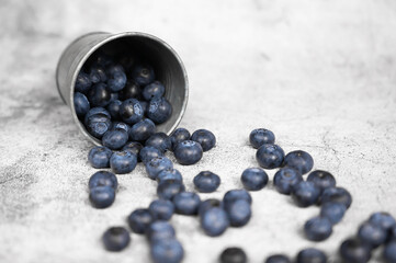 Fresh blueberries falling out of a small metal bucket. Side view. Rustic.