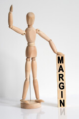 The wooden man raised his hand, and under his left hand he has cubes with the inscription - MARGIN