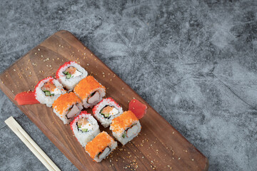 Maki rolls with red caviar topping on a wooden platter