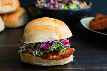 Cajun Chicken Sandwich on a Dark Wood Background: A spicy chicken sandwich topped with coleslaw 
