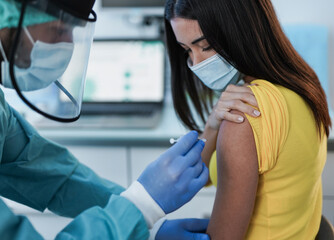 Male doctor vaccine a young woman patient inside hospital - Vaccination against coronavirus pandemic