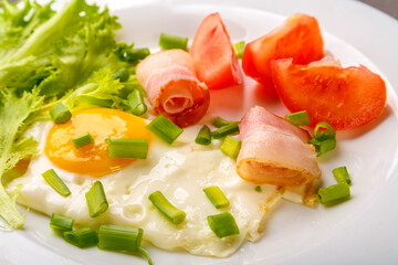 Fried eggs with bacon, tomato and onion close-up.