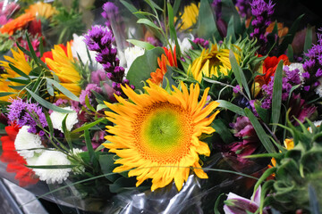 A view of a beautiful flower bouquet, featuring a sunflower, on display at a local florist shop.