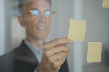 Close up portrait of confident scrum master using sticky notes, scrum for productivity. Handsome smiling businessman planning startup working with agile methodology in modern office, focus on hand  