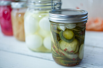 A view of several mason jars filled with a variety of pickled vegetables, featuring cucumber and eggs.