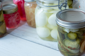 A view of several mason jars filled with a variety of pickled vegetables, featuring cucumber and eggs.