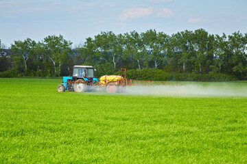 Tractor spraying pesticides at wheat fields