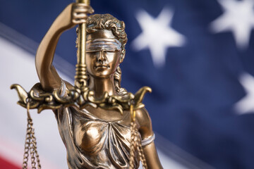 The statue of justice Themis or Justitia, the blindfolded goddess of justice against the flag of the United States of America, as a legal concept