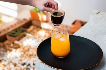 Glass of espresso with orange juice on wooden table and copy space, Summer Cocktail, Cold brew coffee or black tea. (close up, selective focus),