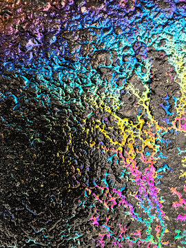 Colorful rainbow colors from an oil spill on the ground