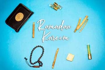 holy book of muslims and siwak ( tooth brush ) and perfume, rosary on blue background. happy ramadan concept