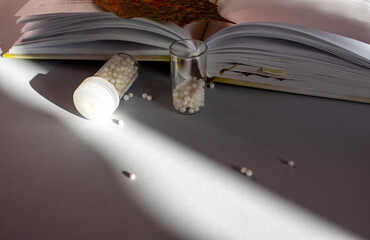 Homeopathic granules in small glass flasks, some granules scattered on the table.