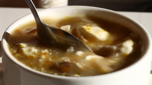 Mushroom soup with sour cream in a bowl, stirring with a tablespoon.