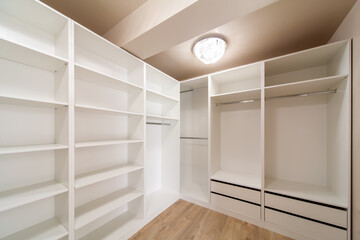Big empty wardrobe in dressing room. Large wardrobe room, with empty shelves. Interior of modern empty dressing room, wardrobe.