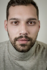 Fototapeta premium Portrait of a young brown-haired man with a short beard and a gray turtleneck sweater