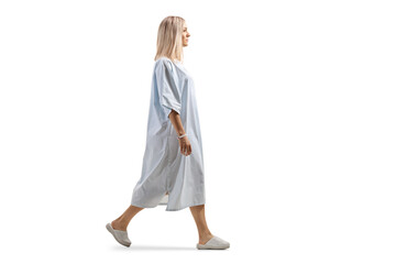 Full length profile shot of a female patient in a gown walking